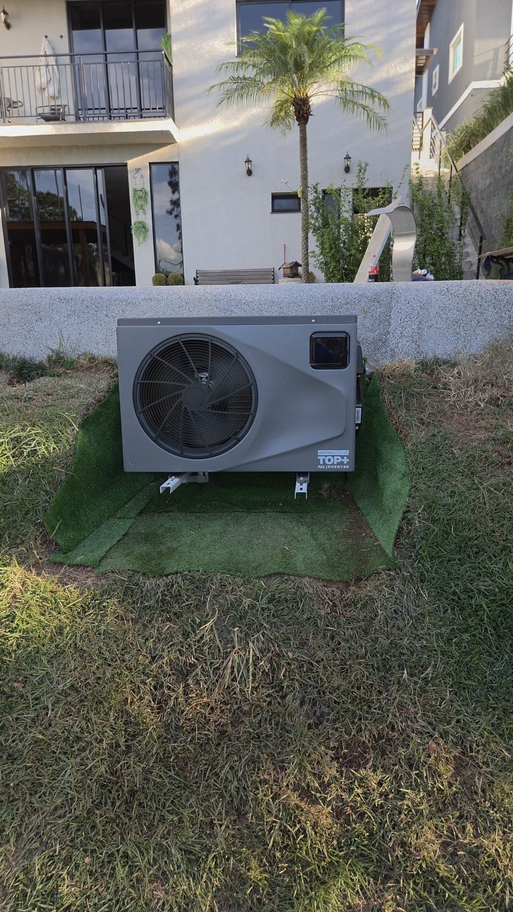 Bomba de calor AstralPool Top+ Full Inverter instalada pela Pointpool ao lado da piscina, em base nivelada no gramado