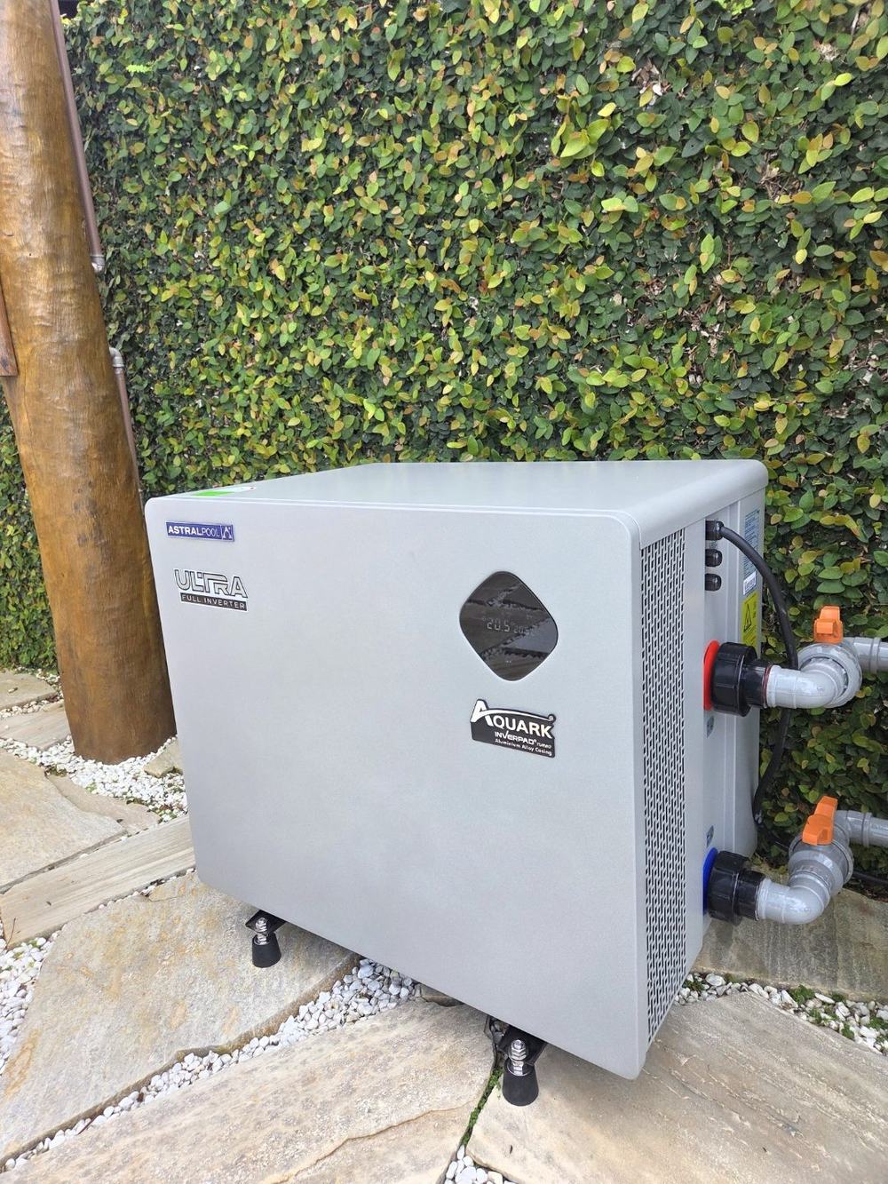 Bomba de calor AstralPool Ultra Full Inverter instalada pela Pointpool em jardim, com conexões hidráulicas e registros