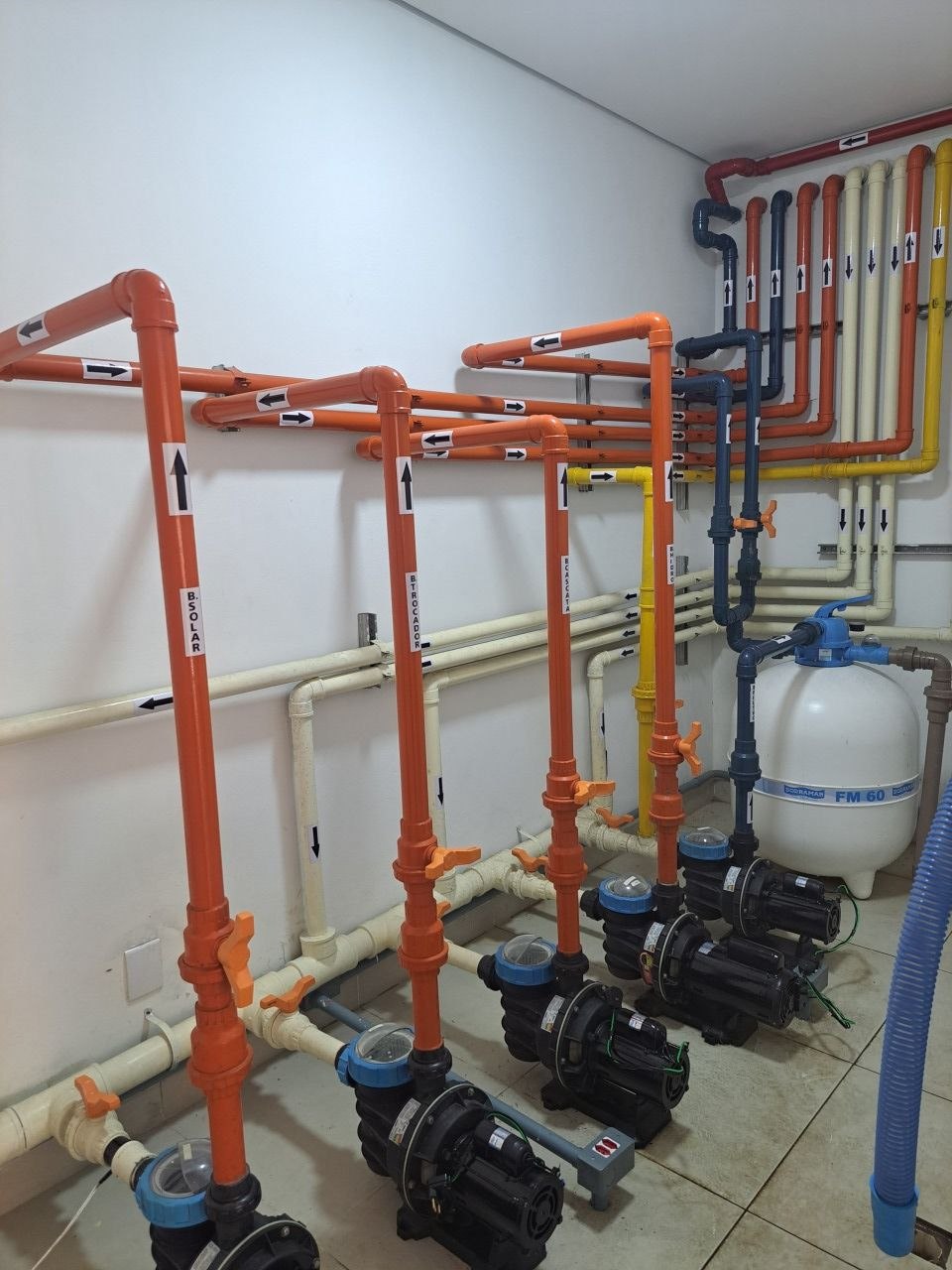 Casa de máquinas de piscina com tubulação identificada: solar, trocador, cascata e hidro
